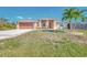 Inviting single-story home showcasing a metal roof, lush lawn, and a spacious driveway leading to a two-car garage at 8230 Agate St, Port Charlotte, FL 33981