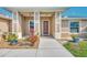 Close-up of a home's entryway featuring decorative columns, a brown front door, and beautiful landscaping at 8230 Agate St, Port Charlotte, FL 33981