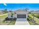 Single-story home featuring a two-car garage and a well-maintained front yard with tropical landscaping at 149 Hercules Dr, Rotonda West, FL 33947