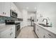 Modern kitchen with stainless steel appliances, white cabinetry, tile backsplash and a large island at 149 Hercules Dr, Rotonda West, FL 33947