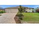 Well-kept exterior with an attached three-car garage, brick paver driveway, and meticulous landscaping at 158 Mariner Ln, Rotonda West, FL 33947