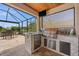 Outdoor kitchen with stainless steel grill, granite counters, and covered seating area at 158 Mariner Ln, Rotonda West, FL 33947