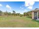 Large grassy backyard featuring lush landscaping and a screened-in patio area at 1909 Johannesberg Rd, North Port, FL 34288