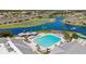 Beautiful aerial view of community pool and lake with fountain views; lush landscape, and paver patio at 24036 Buckingham Way, Port Charlotte, FL 33980