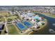 Aerial view of tennis courts, clubhouse, pool, and lake; well manicured grounds and golf cart parking at 24036 Buckingham Way, Port Charlotte, FL 33980