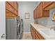 Well-organized laundry room featuring front load washer and dryer, wood cabinets, and a utility sink at 24036 Buckingham Way, Port Charlotte, FL 33980