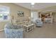 Comfortable living room with neutral decor, tile flooring, and an open layout leading to the kitchen and dining area at 24036 Buckingham Way, Port Charlotte, FL 33980