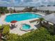 Aerial view of pool with plenty of lounge seating, a hot tub, and lush tropical landscape surrounding it at 24036 Buckingham Way, Port Charlotte, FL 33980