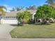 Charming home exterior with well-manicured lawn, palm trees, and a paved driveway at 2479 Sonoma Dr W, Nokomis, FL 34275