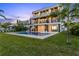 This backyard features a modern three-story house, in-ground pool, and beautifully manicured green lawn at 36 Dolphin Dr, Treasure Island, FL 33706