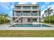 Modern home showcasing a luxurious backyard with a sparkling pool, covered patio, and lush green lawn at 36 Dolphin Dr, Treasure Island, FL 33706
