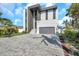 Contemporary two-story home with a gray brick driveway, modern architecture, and lush tropical landscaping at 36 Dolphin Dr, Treasure Island, FL 33706