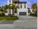 Contemporary three-story home with minimalist design, dark gray garage door, light gray facade, and neatly manicured lawn at 36 Dolphin Dr, Treasure Island, FL 33706