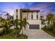 Modern home with a gray driveway and gray garage door, set against lush tropical landscaping at 36 Dolphin Dr, Treasure Island, FL 33706