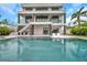 Backyard of a modern three-story home featuring a swimming pool, patio, and a lush green lawn at 36 Dolphin Dr, Treasure Island, FL 33706