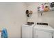 Functional laundry room with modern washer and dryer units and storage shelves above at 3720 Pebble Ter, Punta Gorda, FL 33980