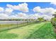 Spacious, green backyard features a black metal fence, lake view, and a small palm tree at 43554 Treadway Dr, Punta Gorda, FL 33982