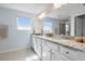 Bathroom featuring double sinks with granite countertops, white cabinetry, and natural light from windows at 43554 Treadway Dr, Punta Gorda, FL 33982