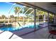 Relaxing screened-in pool and spa with a waterfall feature overlooking a tranquil pond at 483 Corrientes Cir, Punta Gorda, FL 33983