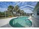 Sparkling pool with screened enclosure and lush landscaping, bright blue skies at 3487 Cabaret St, Port Charlotte, FL 33948