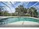 Sparkling pool with screened enclosure and lush landscaping, bright blue skies at 3487 Cabaret St, Port Charlotte, FL 33948