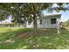 The backyard provides serene outdoor living under the shade of a large mature tree at 5366 Dunsmuir Rd, North Port, FL 34288