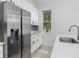 Bright kitchen featuring stainless steel appliances, white cabinetry, and a view of a large tree at 5366 Dunsmuir Rd, North Port, FL 34288