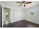 This bedroom features a ceiling fan, closet, dark floors and a view into the bathroom at 556 Lowell Nw Ave, Port Charlotte, FL 33952