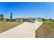 Inviting single-story home featuring an expansive driveway and a charming covered porch at 556 Lowell Nw Ave, Port Charlotte, FL 33952