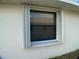 Exterior view of a window with white accordion hurricane shutters on a stucco wall of home at 6170 David Blvd, Port Charlotte, FL 33981