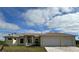 Charming single-story home featuring a two-car garage, light yellow paint, and an expansive front yard with clear blue skies at 6372 Grove Blvd, Punta Gorda, FL 33982