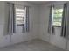 Bright bedroom featuring two windows, soft gray curtains, and stylish flooring at 710 Aqui Esta Dr, Punta Gorda, FL 33950