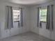 Bright bedroom featuring two windows, soft gray curtains, and stylish flooring at 710 Aqui Esta Dr, Punta Gorda, FL 33950
