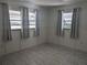 Bright bedroom featuring three windows with privacy blinds, soft curtains, and stylish flooring at 710 Aqui Esta Dr, Punta Gorda, FL 33950
