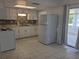 Well-lit kitchen featuring white appliances, modern cabinets, and access to sun room at 710 Aqui Esta Dr, Punta Gorda, FL 33950