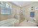 Bright bathroom featuring tiled floors, soaking tub, glass shower and coastal accents at 7346 Talon Bay Dr, North Port, FL 34287