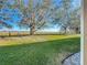Spacious backyard with views of a peaceful grassy field and distant trees at 8858 Tuscany Isles Dr, Punta Gorda, FL 33950