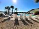 Relaxing poolside with lounge chairs, palm trees, and lake views in a sunny setting at 8858 Tuscany Isles Dr, Punta Gorda, FL 33950