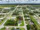 Wide aerial shot capturing a residential area featuring a home on a corner lot surrounded by trees and landscaping at 1022 S Lavina St, North Port, FL 34286