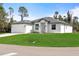 A modern single-Gathering home showcases a white exterior, attached garage, and a lush green lawn at 1022 S Lavina St, North Port, FL 34286