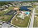 Aerial shot featuring community amenities including a pool, clubhouse, tennis courts, and a tranquil pond at 13468 Romford Ave, Port Charlotte, FL 33981