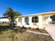 Charming home featuring white exterior with colorful blue door and yellow trim details at 13468 Romford Ave, Port Charlotte, FL 33981