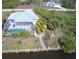 Aerial view showcasing a screened-in pool, patio, and waterfront access with a canal behind the home at 15001 Appleton Blvd, Port Charlotte, FL 33981