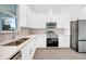 Modern kitchen featuring white cabinets, herringbone backsplash, and stainless steel appliances at 147 Ingram Rd, Rotonda West, FL 33947