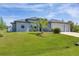 Single-story house with gray siding, a three car garage, and lush lawn at 10721 Ayear Rd, Port Charlotte, FL 33981