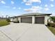 Three-car garage, light colored stucco home, and landscaping at 261 Broadmoor Ln, Rotonda West, FL 33947