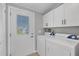 Bright laundry room with washer, dryer, white cabinets, and exterior door at 740 Summersea Ct, Englewood, FL 34223