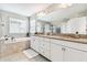 Bathroom with double vanity, granite countertop, and a large soaking tub at 7537 Pool Compass Loop, Wesley Chapel, FL 33545