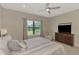 Comfortable bedroom with a ceiling fan, TV, and a window overlooking the backyard at 26950 Pavin Dr, Englewood, FL 34223