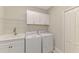 Bright laundry room featuring a washer, dryer, utility sink, and upper cabinets for convenient storage at 26950 Pavin Dr, Englewood, FL 34223